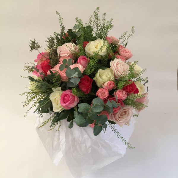 a large bouquet filled with mixed roses in whites, pinks and reds with eucalyptus