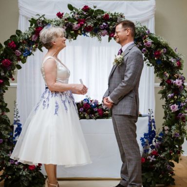 Man and woman getting married in a floral archway